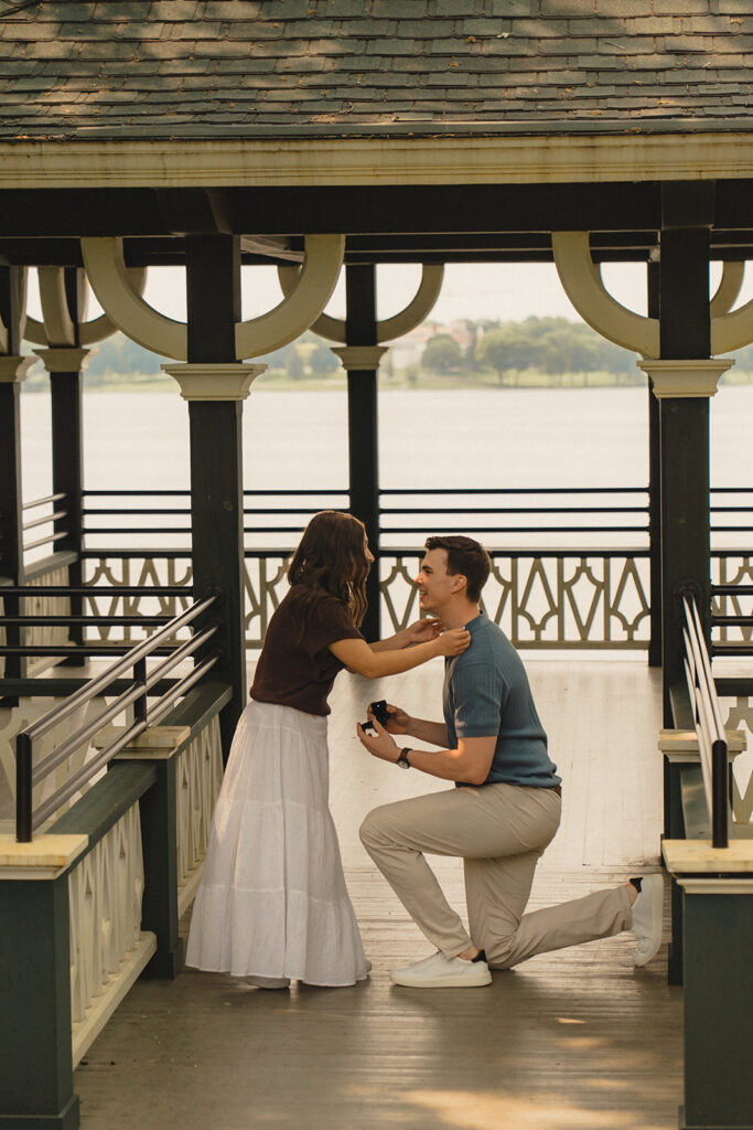 Joey kneeling inside the lakeside gazebo at Noerenberg Gardens as Bella reacts to the proposal.