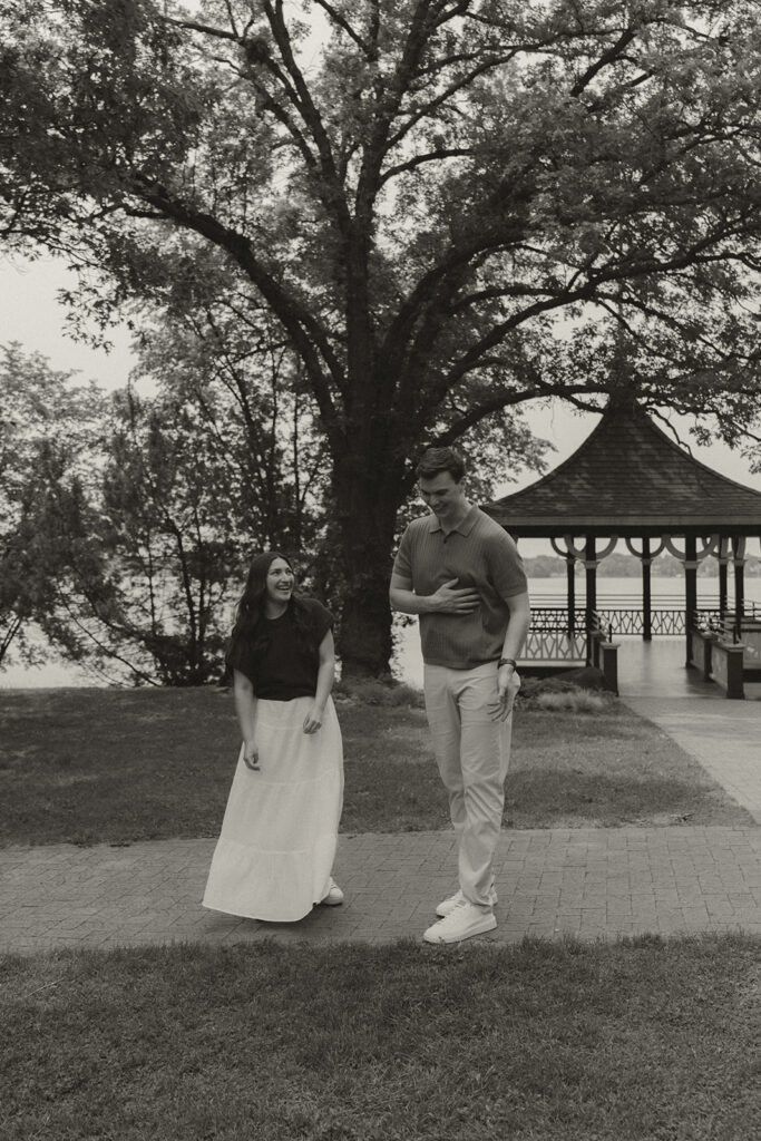 Bella walking toward Joey with a huge smile right after the proposal, the gazebo and lake behind them.