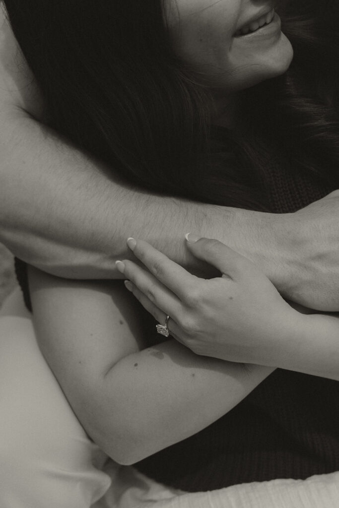 Close-up of Bella’s hands wrapped around Joey’s arm, showing her new engagement ring.