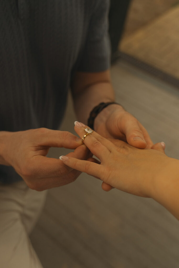 A close-up of Joey placing the engagement ring on Bella’s finger.