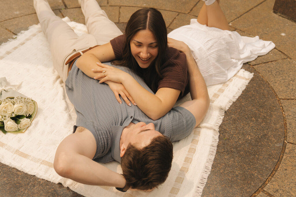 Bella lying on a blanket at Noerenberg Gardens, smiling down at Joey after the proposal.