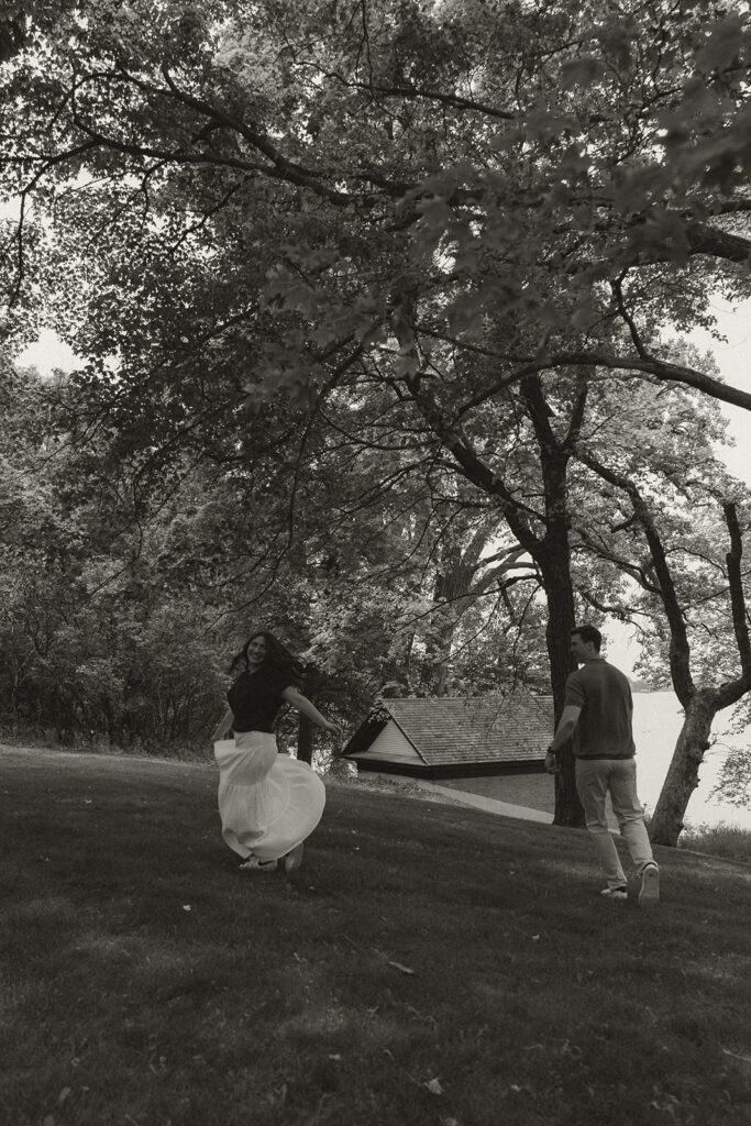 The engaged couple twirling through the park after their wedding proposal photographer captures the 'yes.'