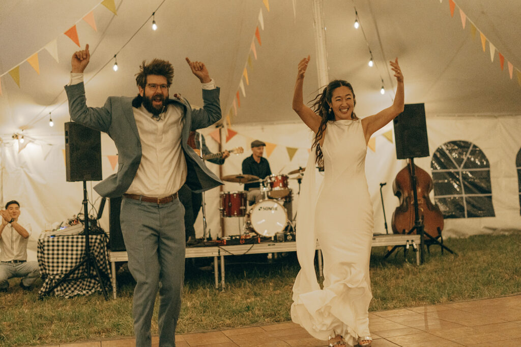 Eura and Stu dancing under the sailcloth tent with a live band behind them, a lively moment from their backyard wedding reception.