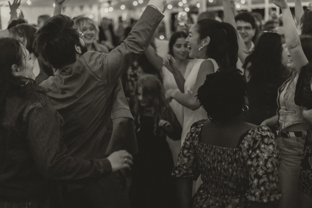Guests crowding the dance floor and celebrating around Eura and Stu, a packed and joyful reception moment under the tent.