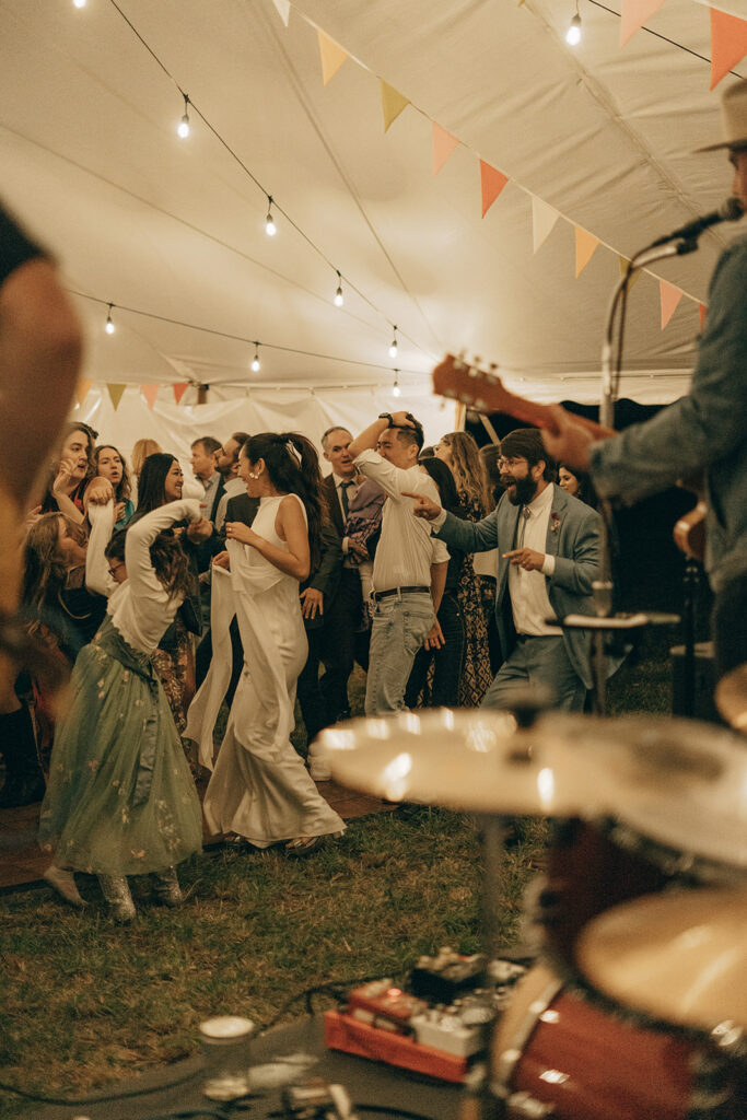 Guests dancing under string lights while the live band plays, a lively backyard wedding dance floor moment.