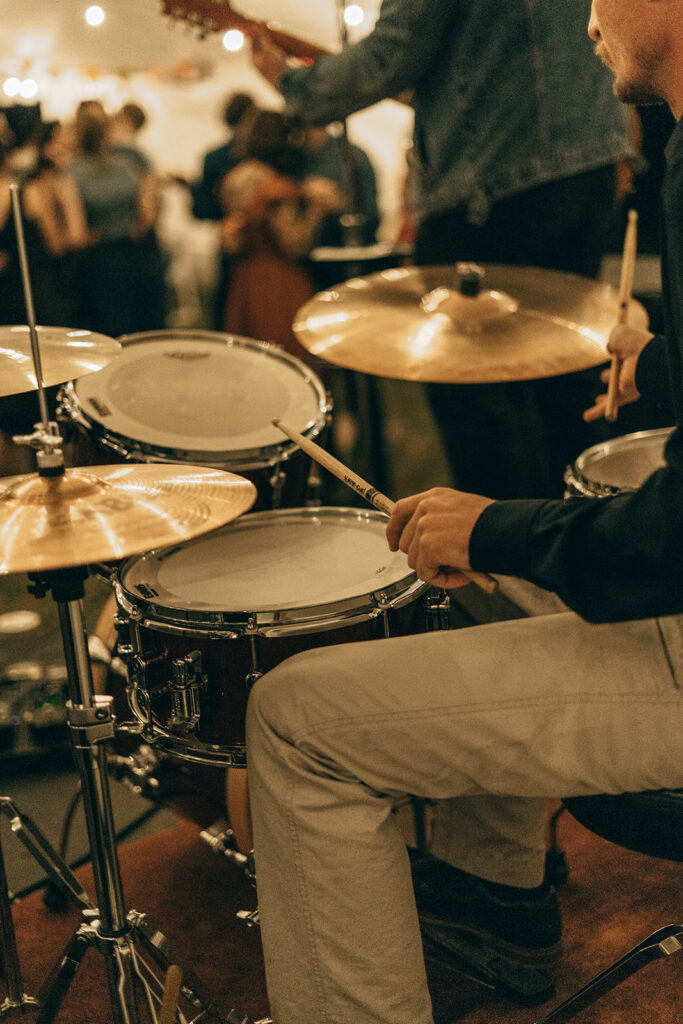 Close-up of the drummer playing during the live band set at the backyard wedding reception, adding energy to the garden party atmosphere.