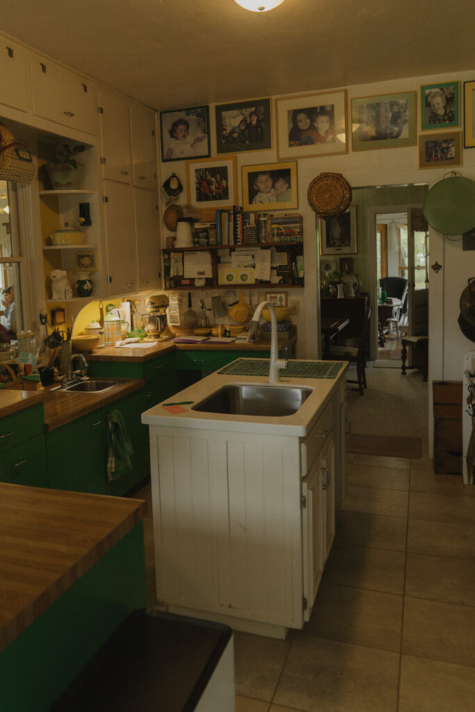 The farmhouse kitchen filled with family photos, green cabinets, and collected treasures where Eura got ready for her backyard wedding at Grandma’s house.