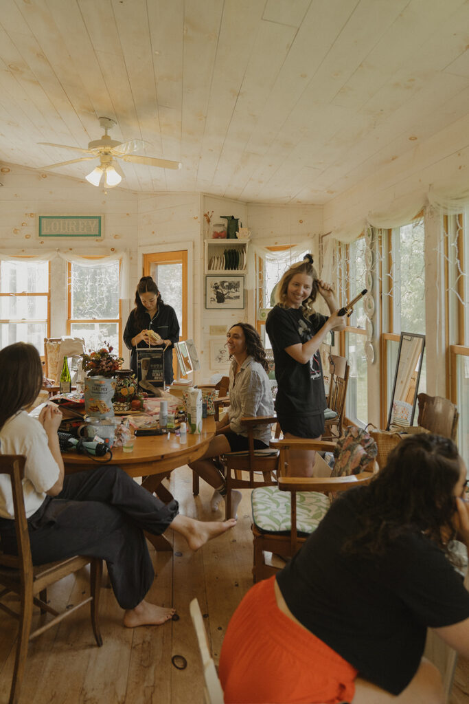 Friends helping Eura get ready in the bright farmhouse sunroom, an easy and intimate start to her backyard wedding day.