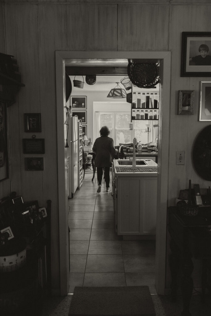 A candid black and white moment of Grandma moving through the farmhouse kitchen on the morning of Eura and Stu’s backyard wedding.