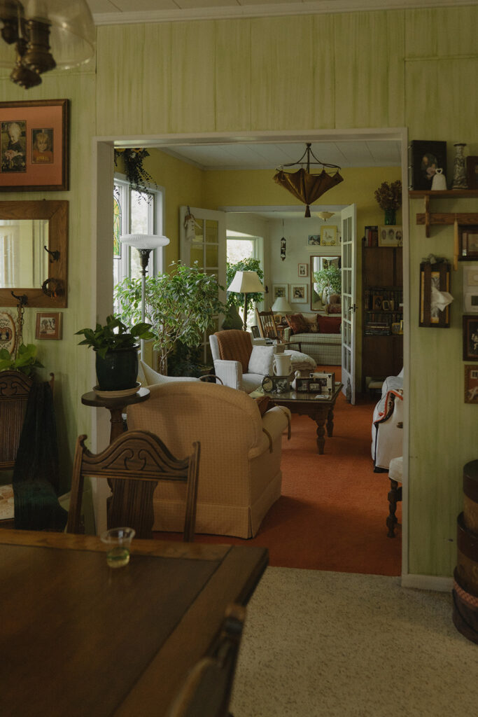 A warm, lived-in living room inside the farmhouse wedding space, filled with plants, artwork, and decades of family memories that shaped the day.