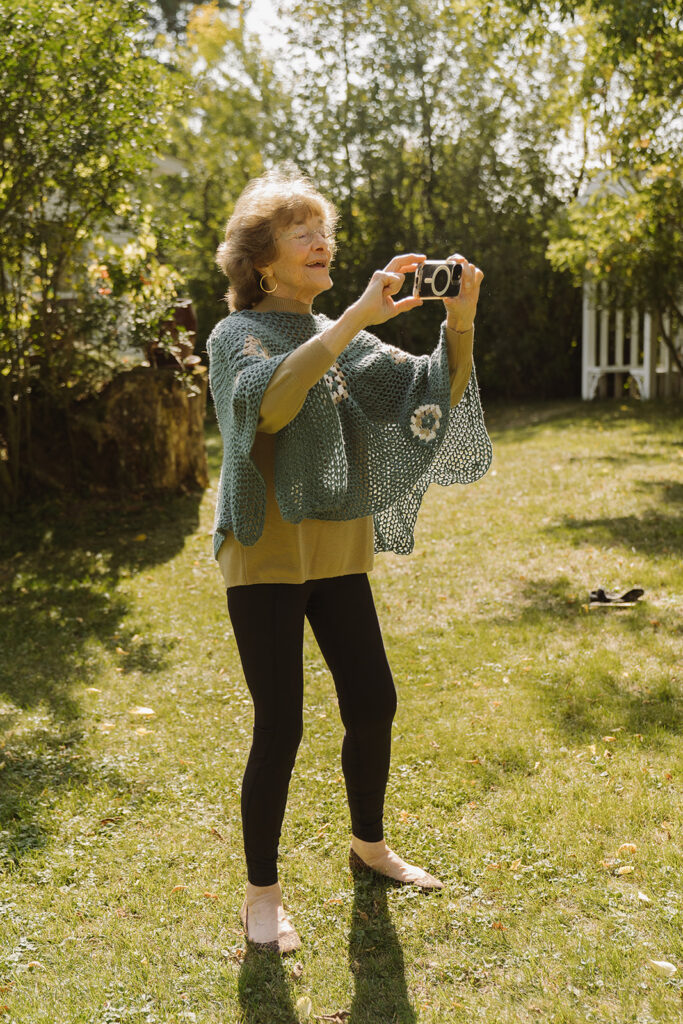 Grandma Becky photographing the couple on her property, capturing a candid moment that reflects the heart of this family-centered backyard wedding.