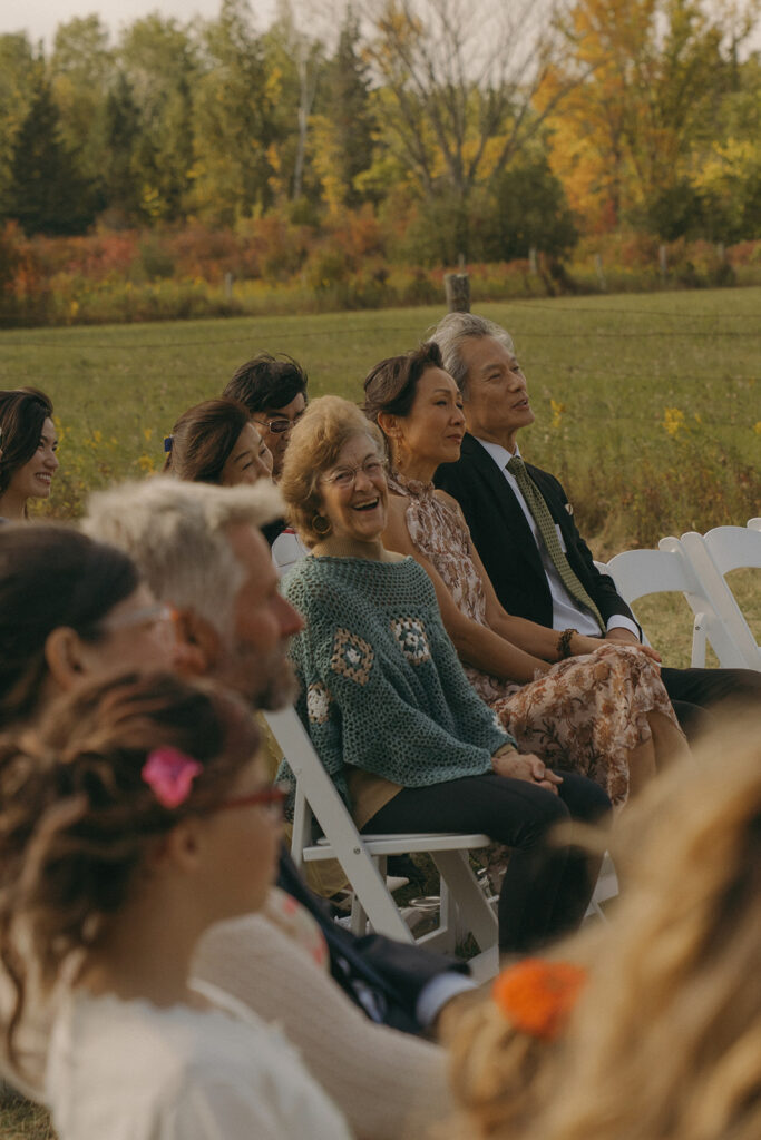 Guests smiling and laughing during the outdoor ceremony, highlighting the relaxed and joyful feel of this backyard wedding.