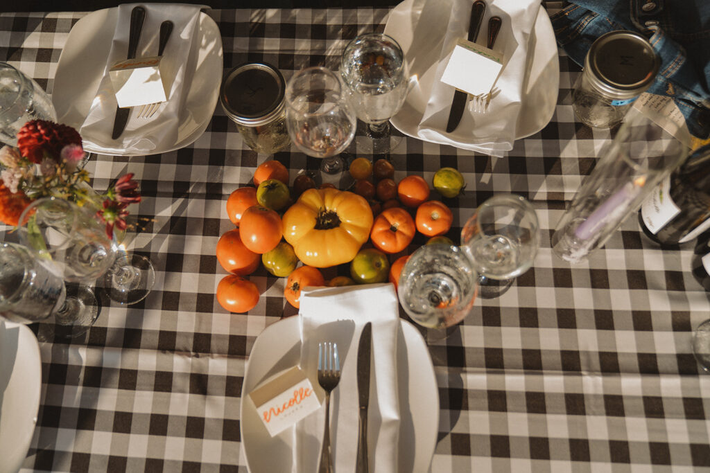 Heirloom tomatoes used as a colorful centerpiece on gingham reception tables at this backyard wedding, a simple garden wedding party décor idea.