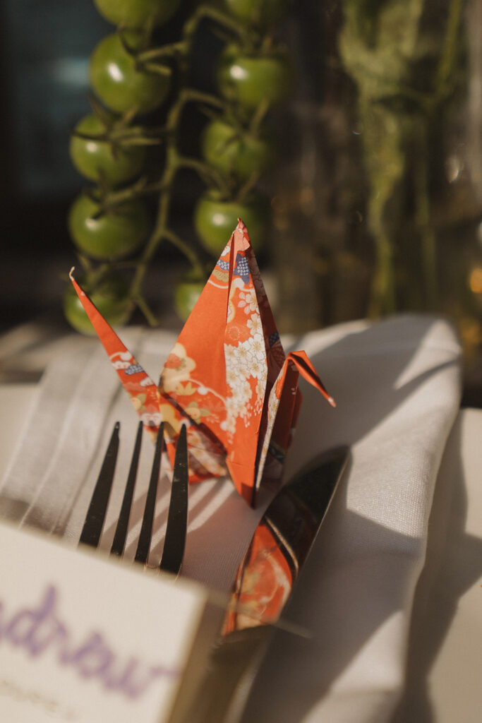 Hand-folded origami crane place card sitting at each table setting, a personal backyard wedding idea that added color and charm.