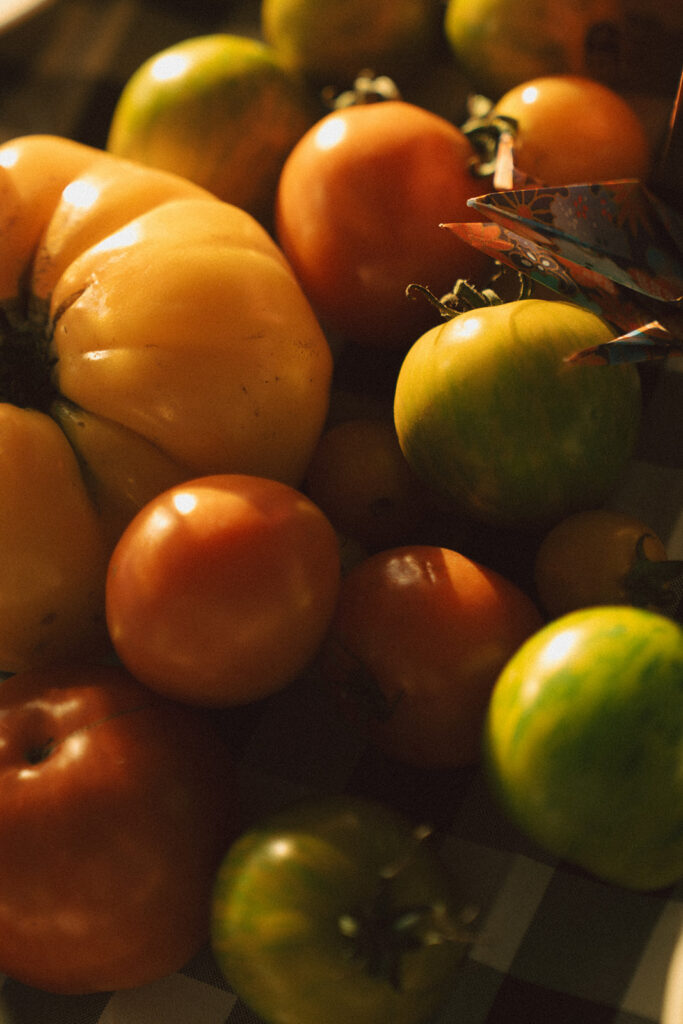 A close-up of heirloom tomatoes used as décor on the reception tables — a simple, colorful backyard wedding idea that added garden-party charm under the sailcloth tent.