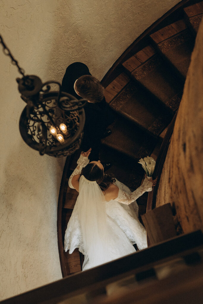 Bride and groom make their way up winding staircase at Edward Anne Estate