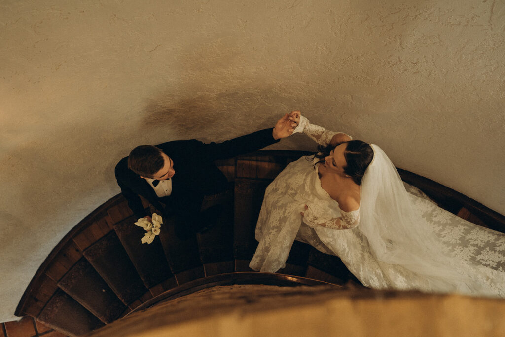 Aerial view of a bride and groom descending a twisted staircase hand in hand at Edward Anne Estate
