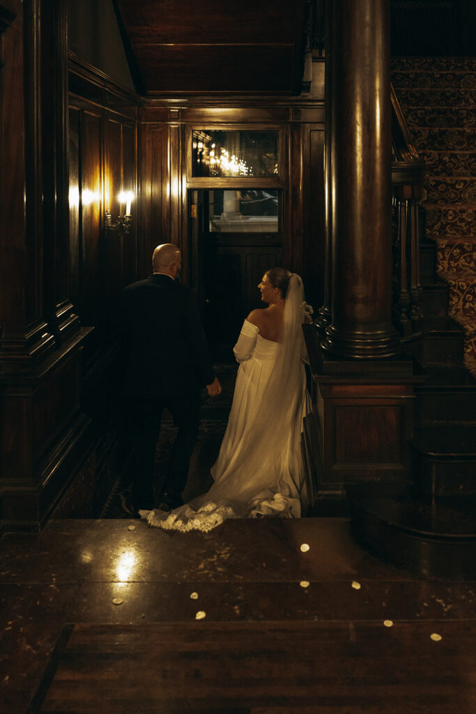 Newlyweds walk down dark walnut halls of Semple Mansion after their vintage wedding