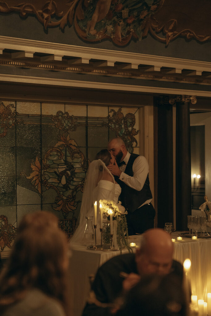 Bride and groom kiss at head table in their vintage wedding pics