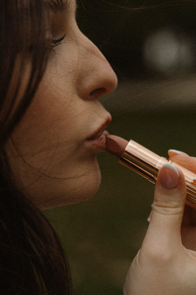 Close crop of bride applying a layer of lipstick in iconic vintage wedding pics