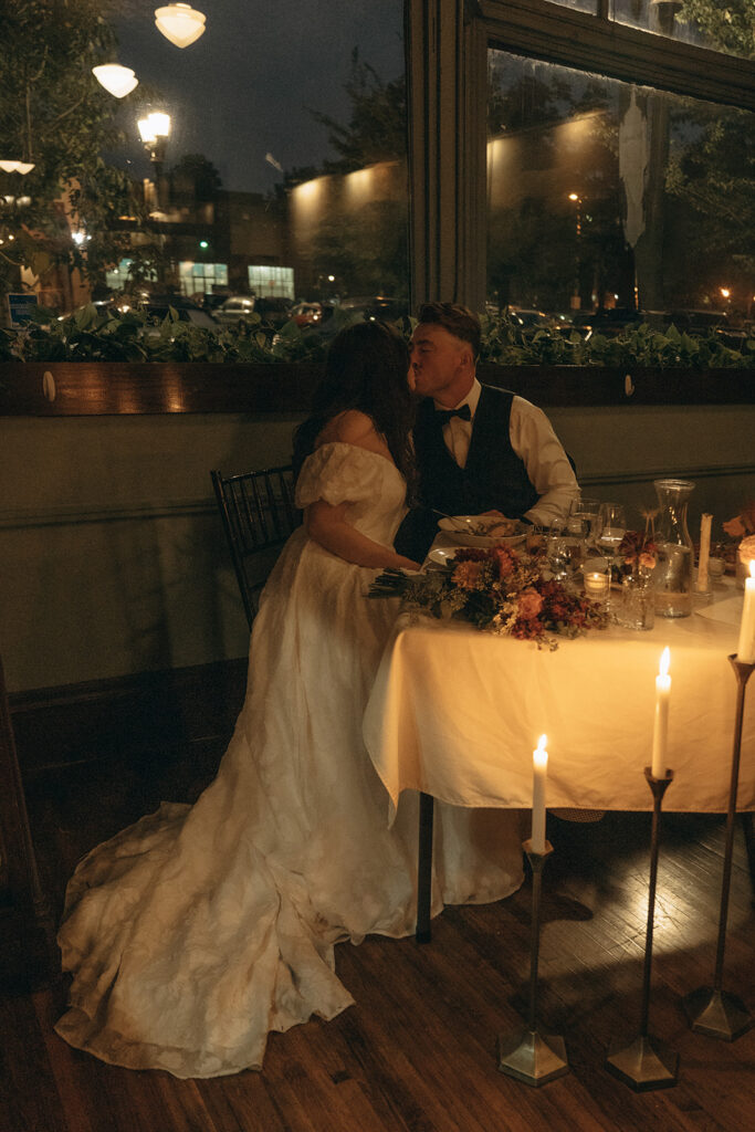 Bride and groom kiss at the end of their wedding night, framed by taper candlelight at WA Frost and Company in Saint Paul, Minnesota