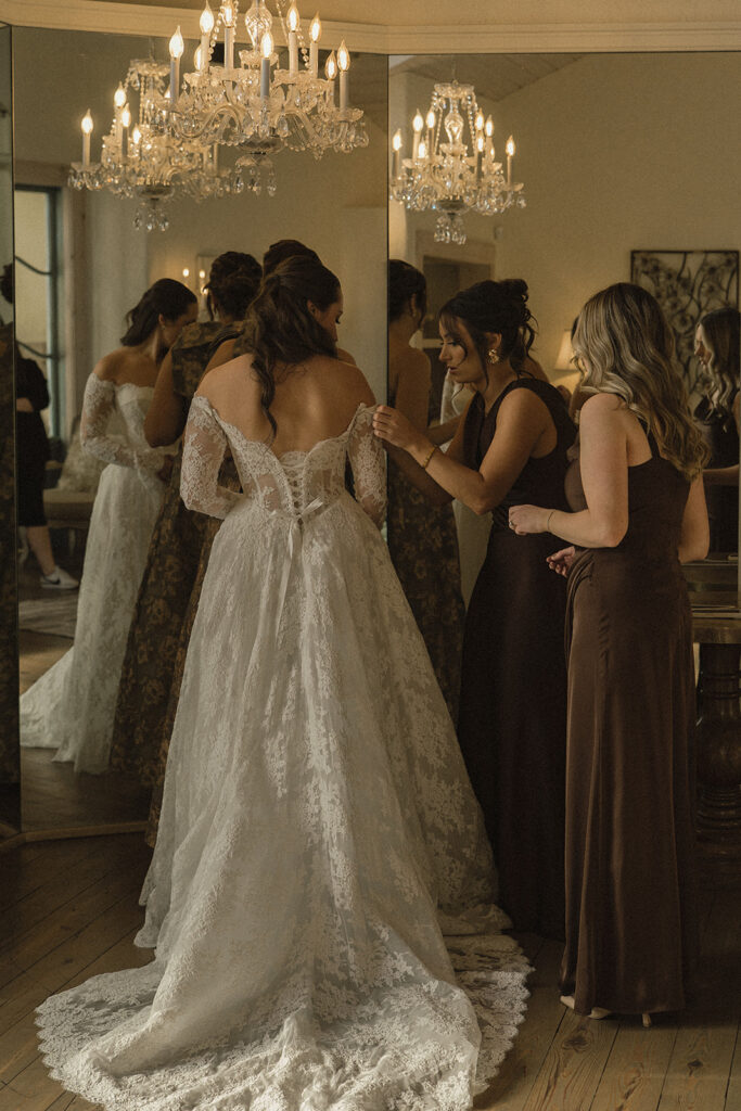 Bridesmaids help vintage wedding bride fix her dress before the ceremony at Edward Anne Estate