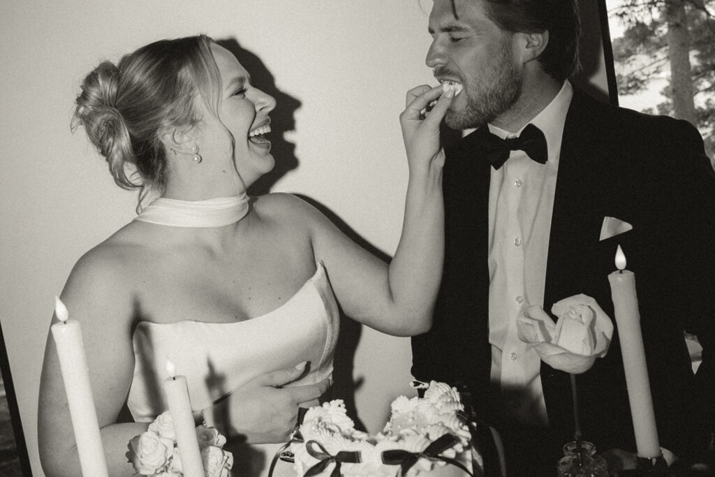 Bride playfully feeds groom a chunk of cake during wedding cake pictures