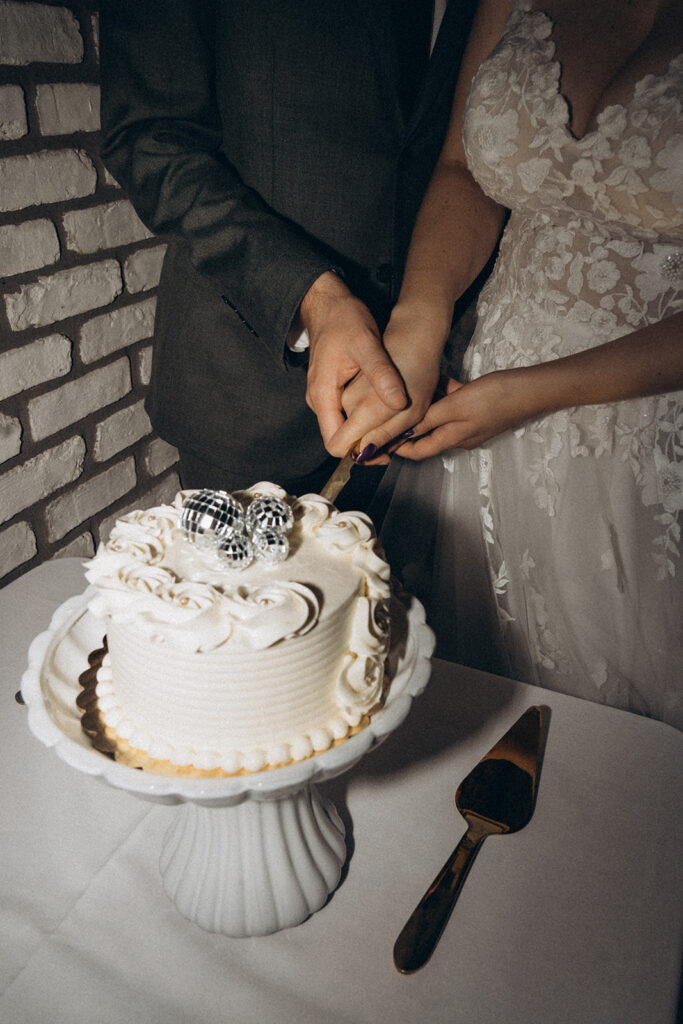Bride and groom cut into their wedding cake together during their first task as husband and wife