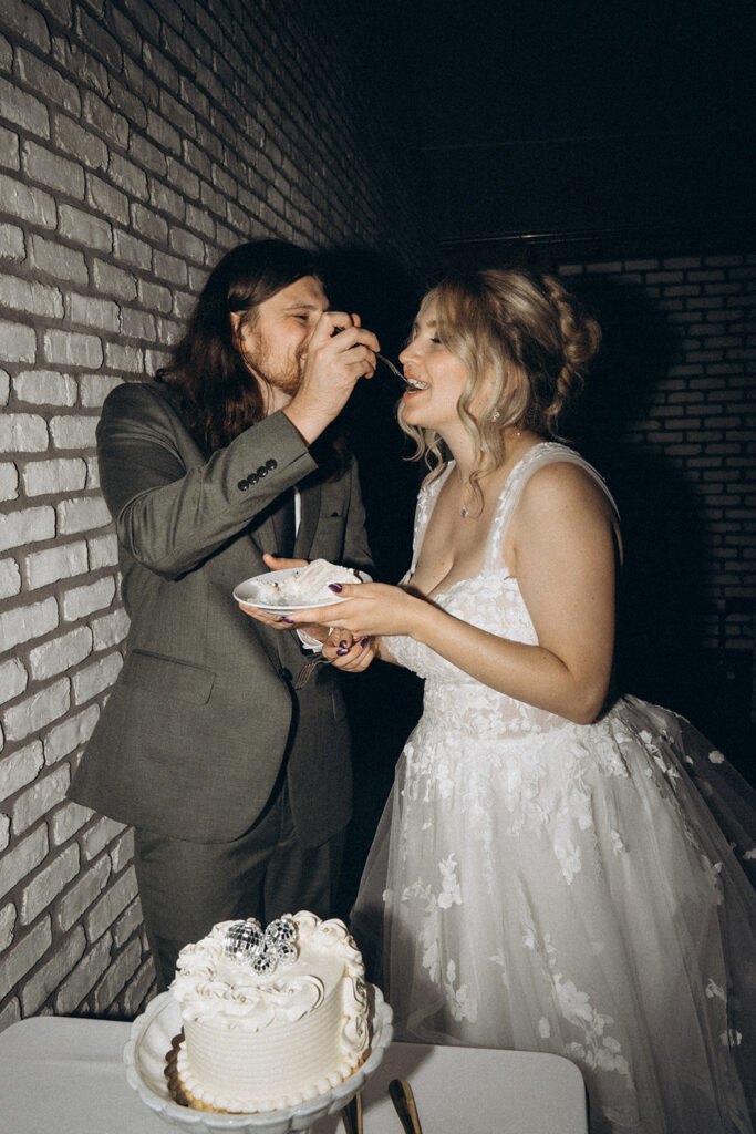 Wedding cake pictures with groom playfully feeding bride a bite off of his fork