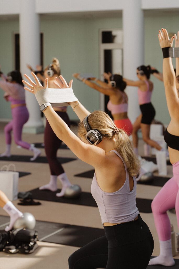 Woman raising arms during sculpt class, dynamic branding photos for Garnuu.