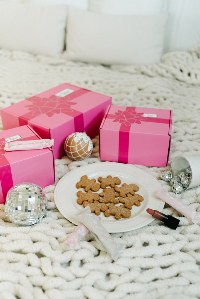 Pink Garnuu gift boxes beside cookies and disco ball on chunky knit blanket, holiday brand photoshoot idea.