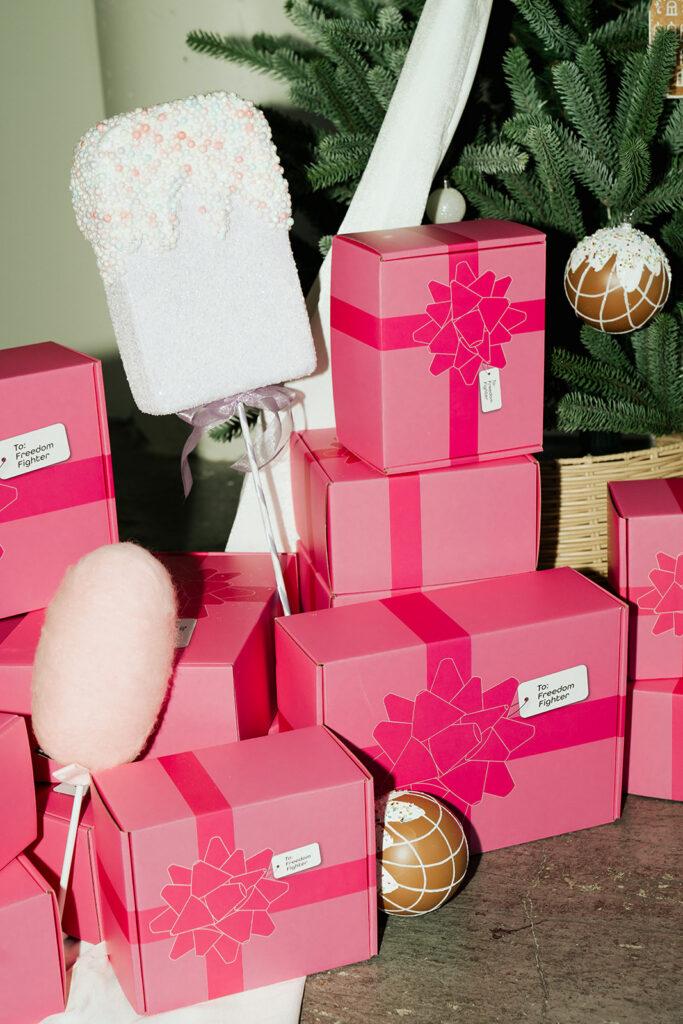 Stack of Garnuu gift boxes beside holiday décor and tree, seasonal product branding photos.