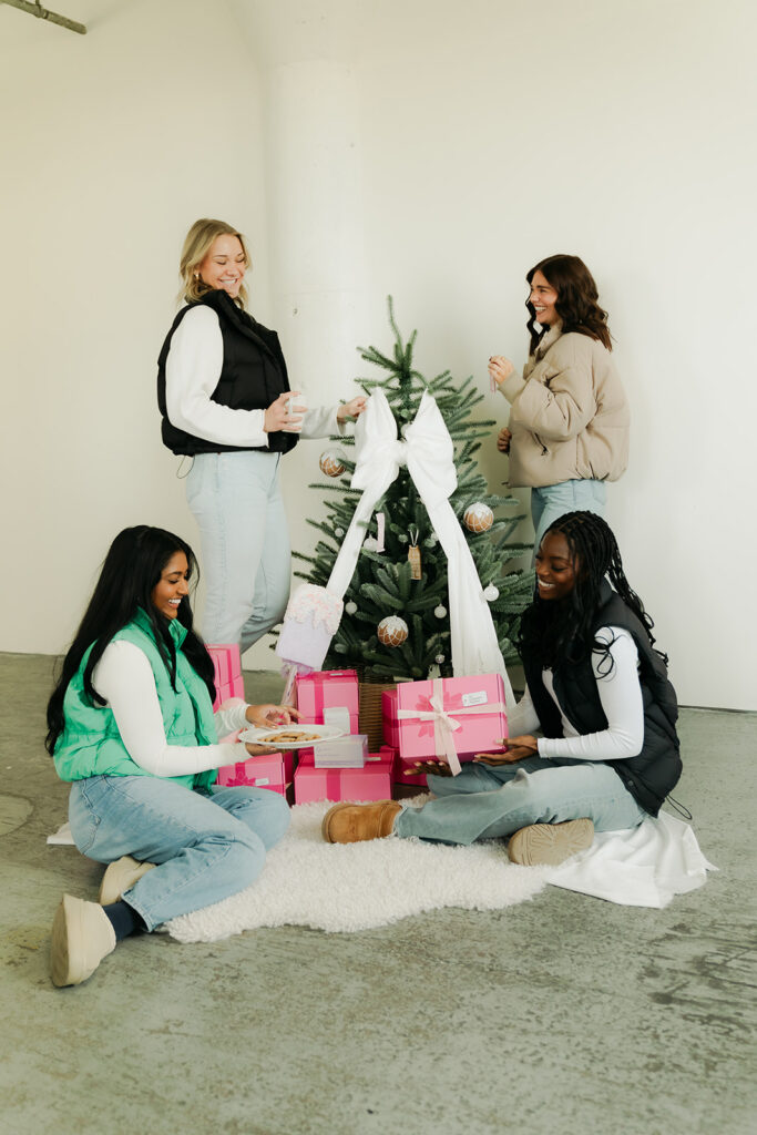 Women gathered around Christmas tree opening Garnuu gifts, warm branding photos for Garnuu.