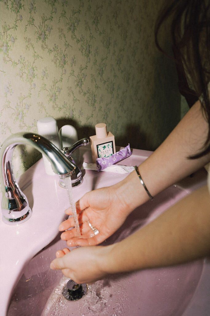 Hands washing at a pink sink surrounded by Garnuu products in lifestyle branding photos for a modern wellness brand.