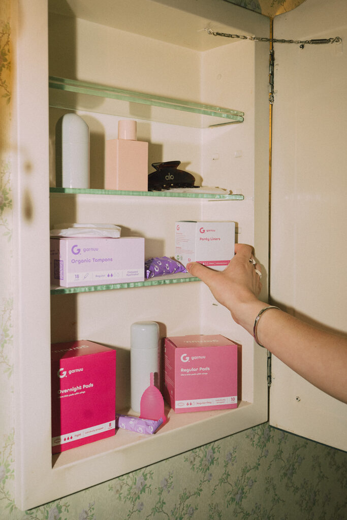 Open medicine cabinet styled with Garnuu packaging and feminine wellness products, a clever brand photoshoot idea with retro charm.