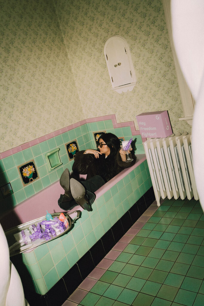 Woman lounging in vintage mint bathtub holding Garnuu products, fashion-forward branding photos for Garnuu.