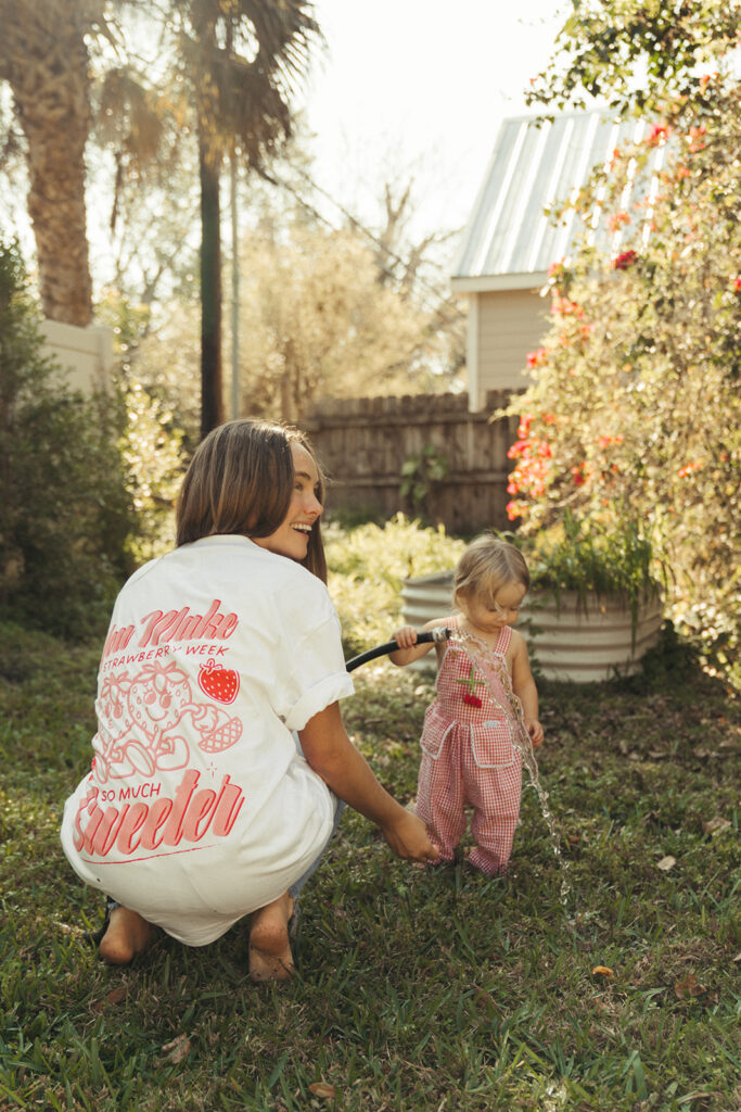 Mother crouching with toddler in yard while wearing Garnuu tee, approachable branding photos.