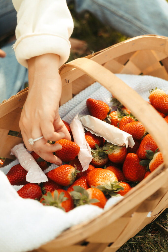 Hand selecting strawberries from basket with Garnuu product tucked inside, clever brand photoshoot idea.