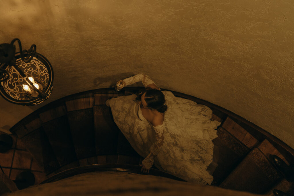 Bride glides down steps of Estate Anne Estate with a glass of wine in hand