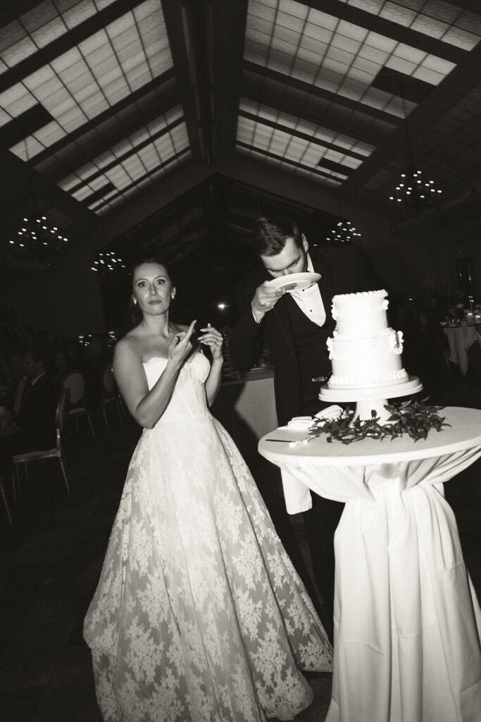 Bride caught in the act of licking her frosting-covered fingers while groom licks frosting directly from the plate in fun wedding cake pictures