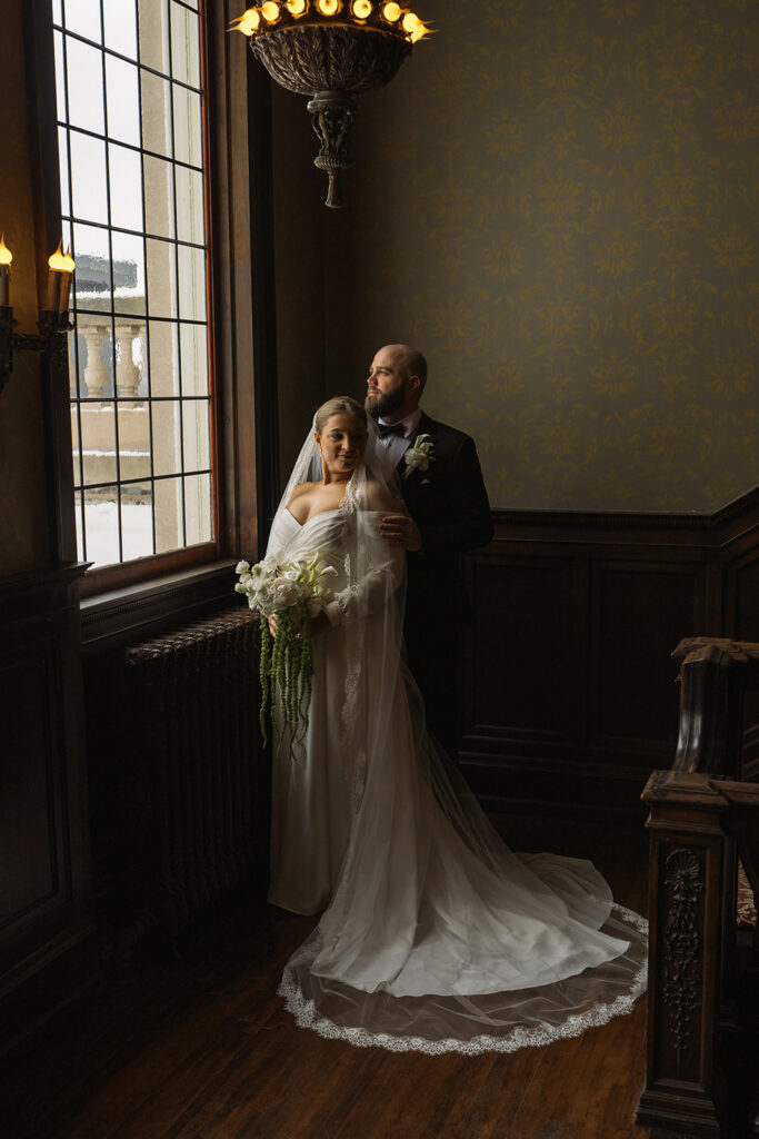 Bride and groom stand in window light in historic wedding venue in Saint Paul, Minnesota