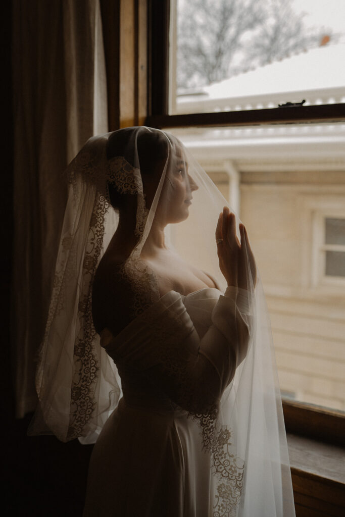 Bride looks out of her sheer veil over the courtyard of Semple Mansion in Minnesota