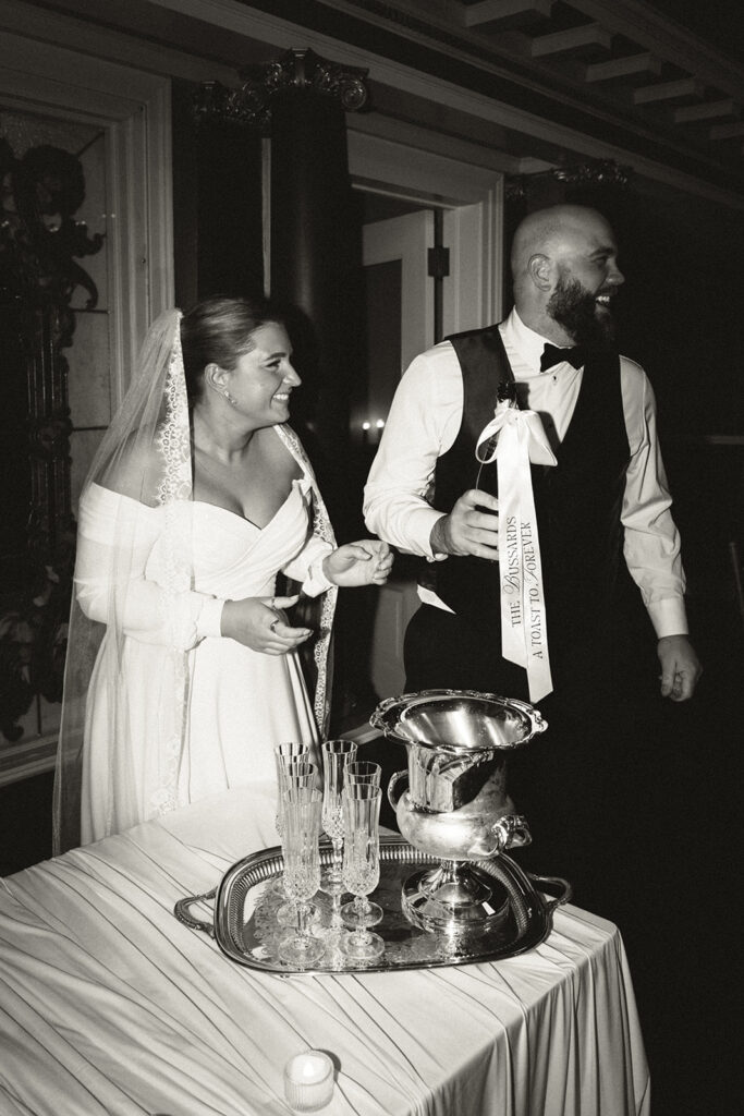 Bride and groom laugh at something out of frame during their champagne pour moment