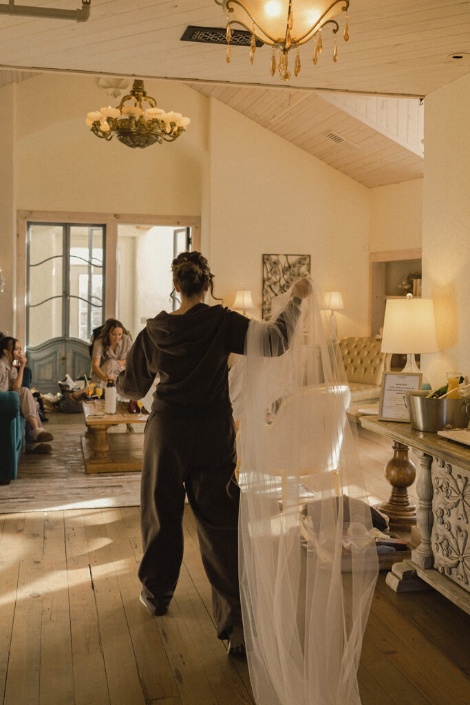 Bridesmaid carries veil through bridal suite at historic wedding venue