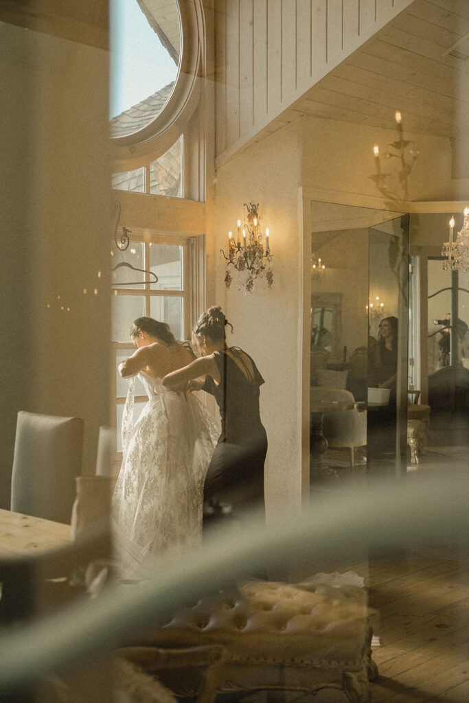 Mother of the bride helps bride put on her dress in bridal suite at Edward Anne Estate