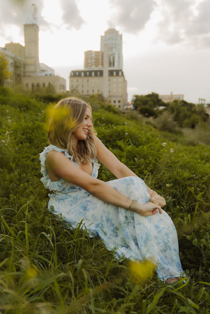 Young girl sits in long grass with the Twin Cities skyline behind her