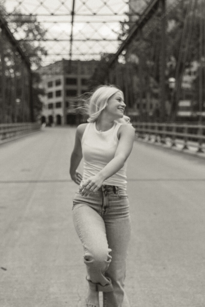High schooler skips across a bridge in carefree senior photos
