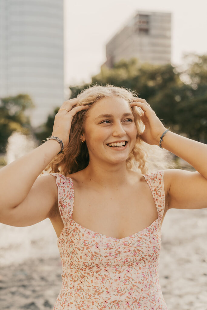Young girl brushes her curls behind her ears as the Minneapolis skyline towers in the distance