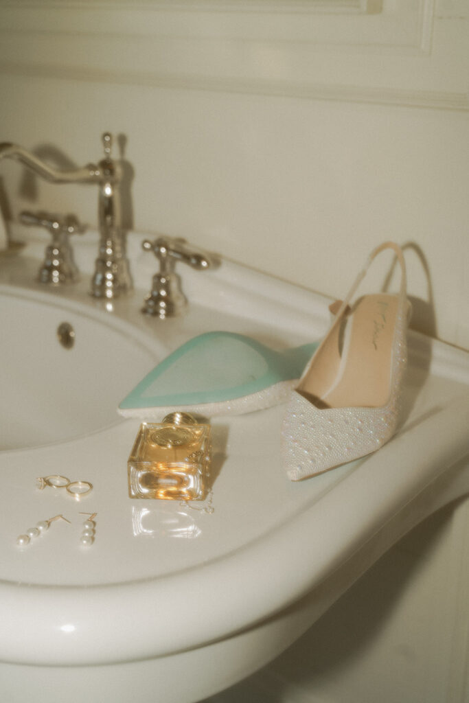Bridal details lay on edge of porcelain sink at historic wedding venue in Minneapolis, Minnesota