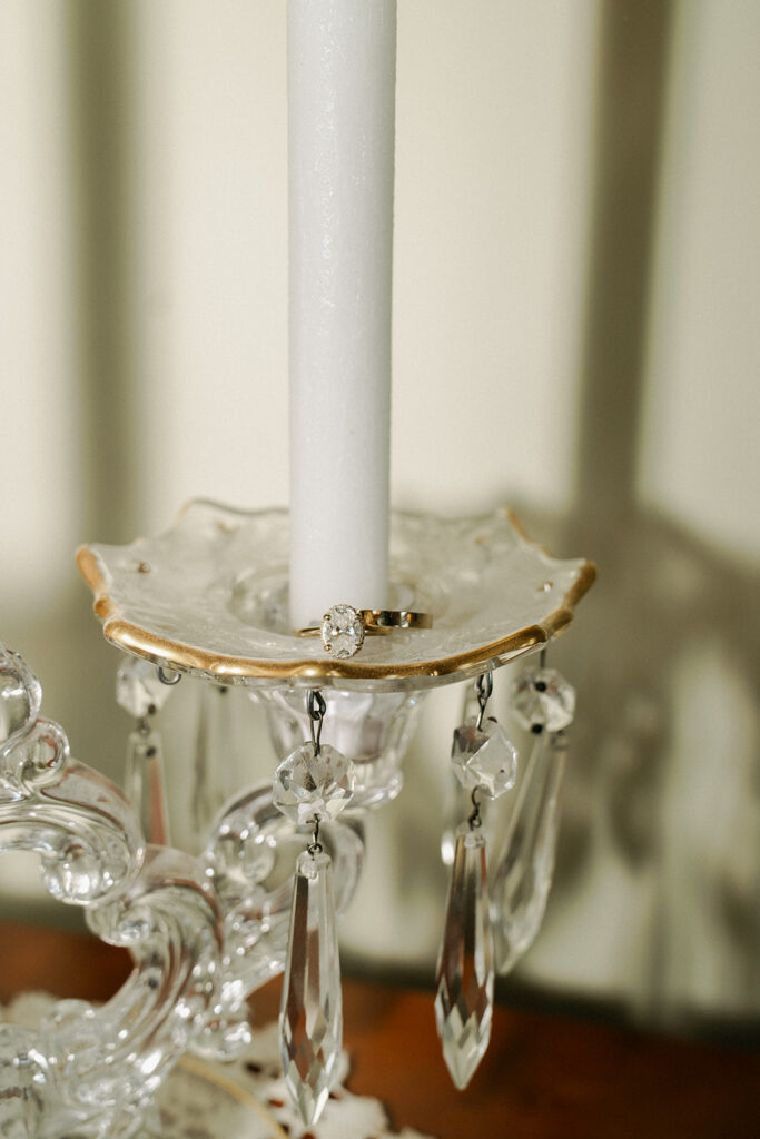Bride's engagement ring sits on tape candle holder dish with crystal